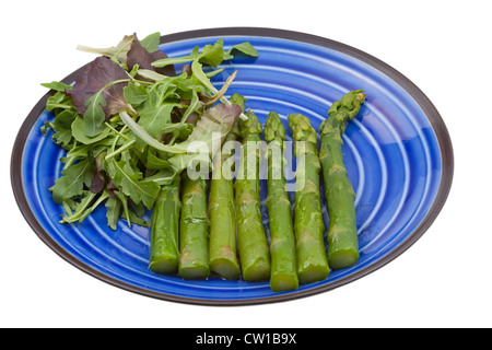 Bollito di asparagi verdi con insalata mix su piastra blu Foto Stock