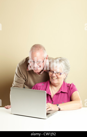 Senior l uomo e la donna utilizzando portatile mentre cercando felice Foto Stock