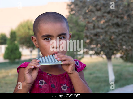 Ragazza giovane con la testa rasata giocando pan tubazioni, Khiva, Uzbekistan Foto Stock