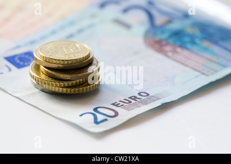Banconote e monete in euro su uno sfondo bianco. Foto Stock