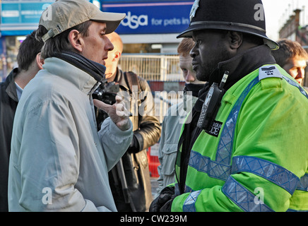 Nero di un funzionario di polizia che parla con un EDL (Inglese Lega della difesa) sostenitore sulle strade di Barking, Essex, Londra, durante un rally Foto Stock