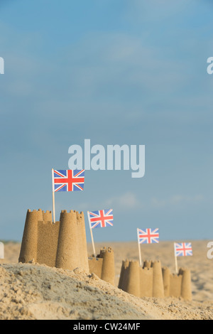 Union Jack Flag in castelli su una spiaggia. Pozzetti accanto al mare. Norfolk, Inghilterra Foto Stock