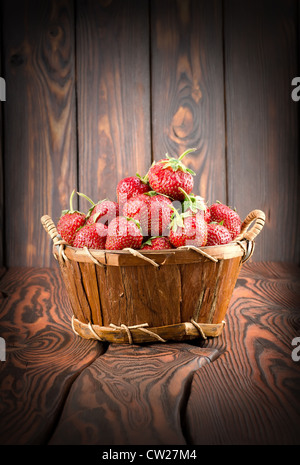 Le fragole in un cesto su uno sfondo di legno Foto Stock