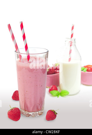 Frullato di fragole in vetro con cannucce, bottiglia di latte e frutta in background Foto Stock