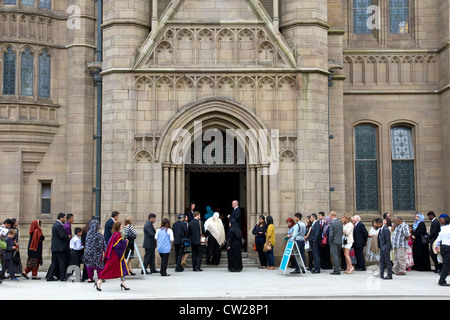 Le famiglie e gli ospiti in coda per la cerimonia di laurea, Whitworth Hall dell'Università di Manchester, Manchester, Inghilterra, Regno Unito Foto Stock