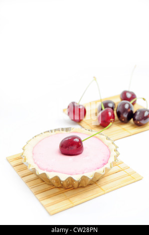 Torta decorata con la ciliegia e le ciliegie in background Foto Stock