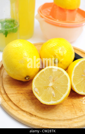 Limoni come ingredienti per la limonata, bottiglie e strizzatore in background Foto Stock