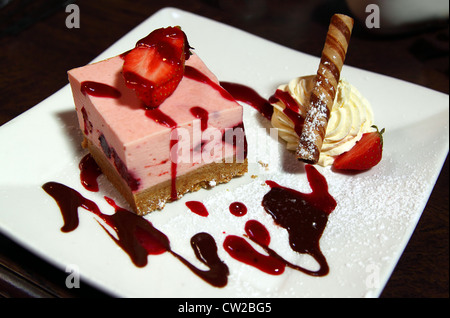 Un delizioso cheesecake con fragole e panna Foto Stock