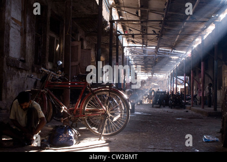 Operaio lavora con i suoi strumenti seduta accanto alla sua bicicletta - mercato Crawford, Mumbai - India Foto Stock