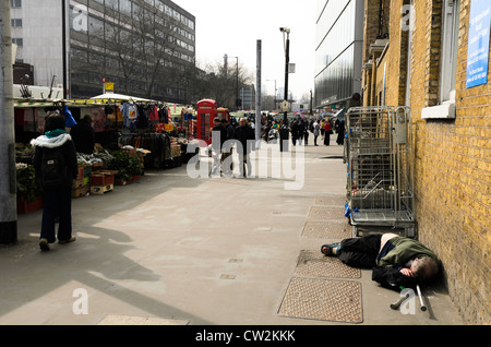 Senzatetto che dorme sul terreno in prossimità di Whitechapel mercato - Londra, Inghilterra Foto Stock