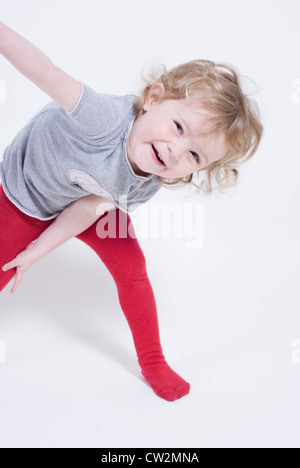 Bambina che mostra Off ridere e Stretching chinarsi, ritratto in studio tagliati su bianco Foto Stock