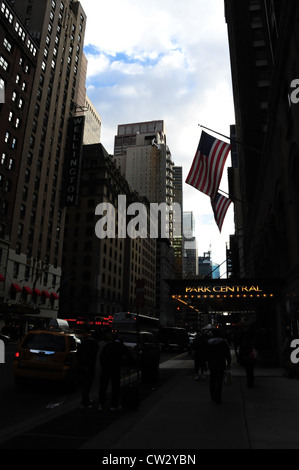 Cielo grigio ora di punta vicolo urbano ritratto, automobili, bandierine americane, luci elettriche marquee Park Central Hotel, 7th Avenue, New York Foto Stock
