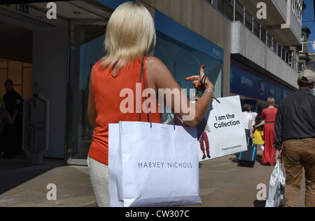 Una donna con un po' di sistemazione di sacchi da asporto a piedi lungo Princes Street di Edimburgo. Foto Stock