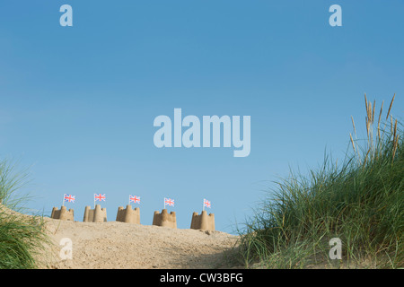 Union Jack Flag in castelli su una duna di sabbia. Pozzetti accanto al mare. Norfolk, Inghilterra Foto Stock