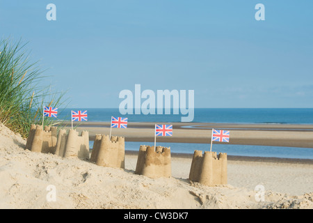 Union Jack Flag in castelli su una duna di sabbia. Pozzetti accanto al mare. Norfolk, Inghilterra Foto Stock