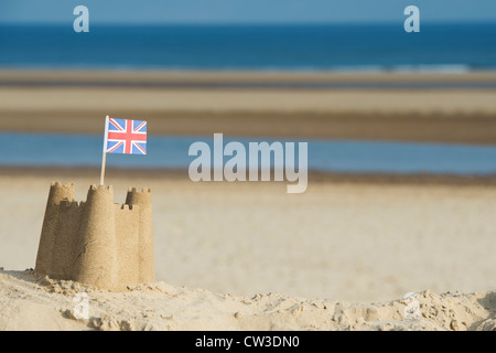 Union Jack flag in un castello di sabbia su di una duna di sabbia. Pozzetti accanto al mare. Norfolk, Inghilterra Foto Stock