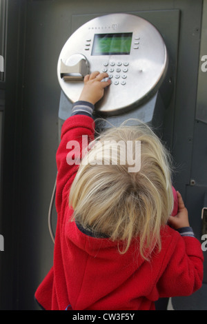 Berlino, un bimbo al telefono in una cabina telefonica Foto Stock