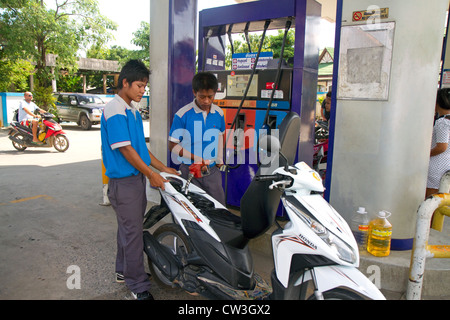 Gas station attendant riempiendo uno scooter a motore sull isola di Ko Samui, Thailandia. Foto Stock