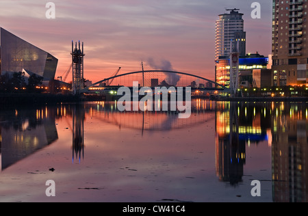 Un bel cielo rosa a Salford Quays dipinge Millineum Bridge, Imperial War Museum e Lowry Foto Stock