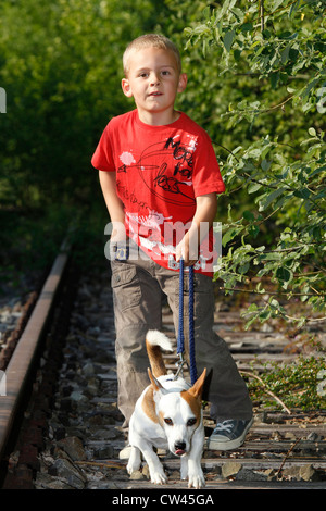Ragazzo con il suo misto di razza di cane che corre lungo la ferrovia in disuso via Foto Stock