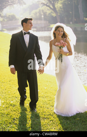 Sposa giovane camminare insieme tenendo le mani Foto Stock