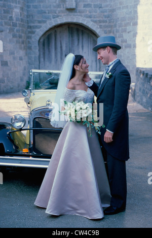 Sposa giovane in piedi di fronte a un antico auto Foto Stock