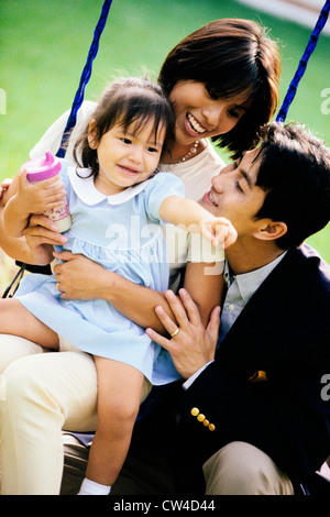 Close-up dei genitori a giocare con la loro figlia su un altalena Foto Stock