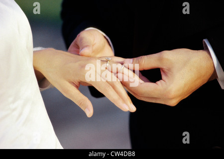 Close-up di un groom collocando un anello al dito della sposa Foto Stock