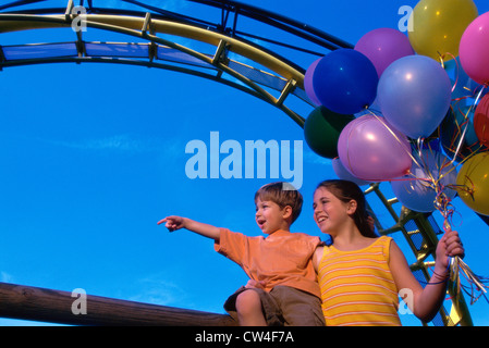 Basso angolo di visione di un fratello e una sorella in un parco di divertimenti Foto Stock