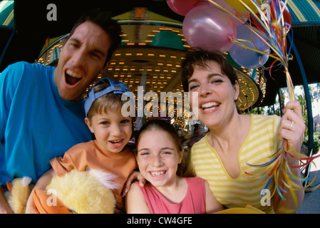 Close-up dei genitori con il figlio e la figlia in un parco di divertimenti Foto Stock