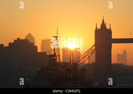 Londra, Inghilterra. Sunrise dietro il Tower Bridge, HMS Belfast in primo piano. Foto Stock