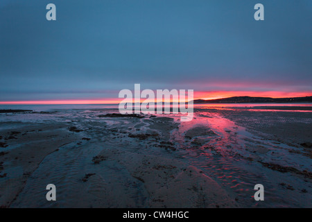 Tramonto su una spiaggia in Galles mostra red sky Foto Stock