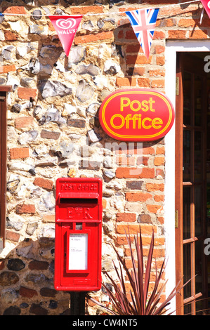 Royal Mail red casella di posta al di sotto di un ufficio postale firmare in un piccolo villaggio di Norfolk Foto Stock