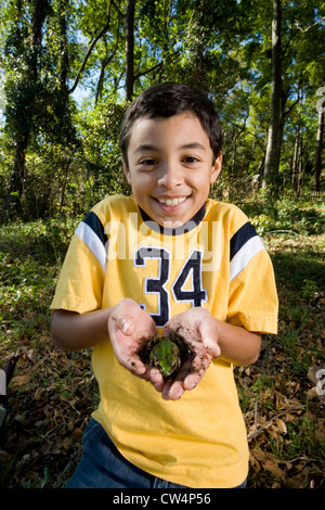Ritratto di un allegro ragazzo tenendo una rana nel suo palm a forest Foto Stock