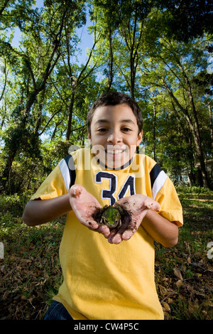 Ritratto di un allegro ragazzo tenendo una rana nel suo palm a forest Foto Stock