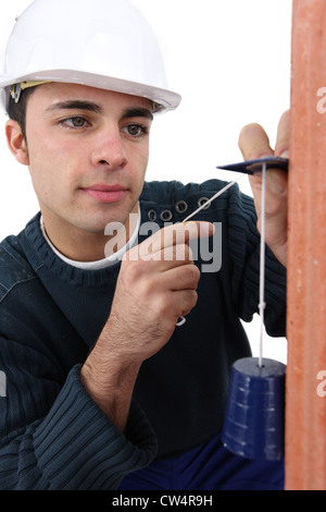 Lavoratore utilizzando un filo a piombo Foto Stock