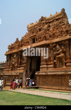 La gente che camminava per la grande entrata in pietra pareti riempite con sculture indù in Tanjore Tempio Brihadeeswara in India del Sud Foto Stock
