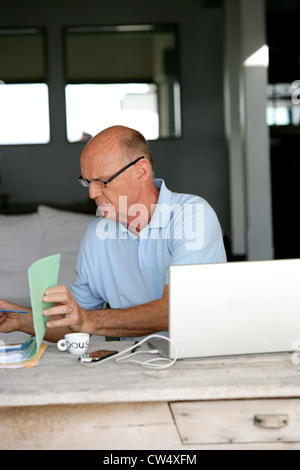 Senior uomo cercando di ordinare hiss casa fatture fuori Foto Stock