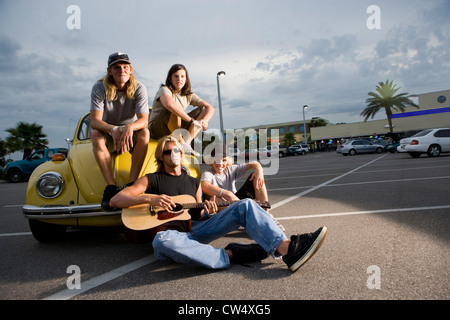 Ritratto di amici gustando la musica da un auto presso il parcheggio Foto Stock