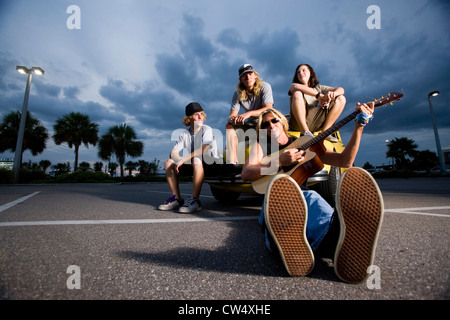 Ritratto di amici gustando la musica da un auto presso il parcheggio Foto Stock