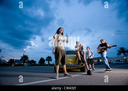 Gli amici ascoltare musica da un auto presso il parcheggio Foto Stock