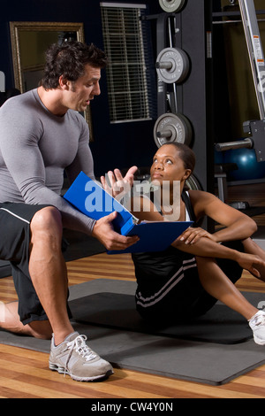 Trainer e una giovane donna impegnata nella conversione in palestra Foto Stock