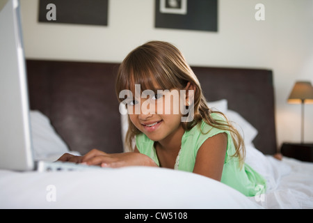 Ritratto di una ragazza che giace nel letto e utilizzando un computer portatile Foto Stock