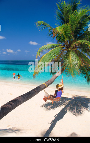 Matura in esecuzione in acqua e la donna in amaca sulla isola di Fihalhohi delle Maldive Foto Stock