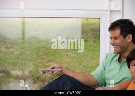 Uomo maturo con suo figlio a guardare la televisione e sorridente Foto Stock