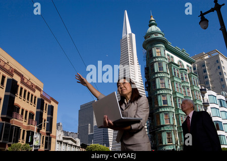 Imprenditrice azienda portatile con imprenditore in piedi dietro la sua Piramide Transamerica e Columbus Torre San Francisco Foto Stock