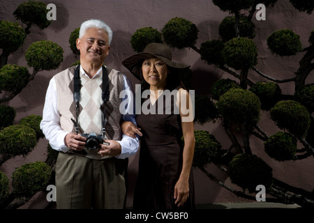 Uomo maturo in piedi con una donna matura e in possesso di una fotocamera e sorridente Foto Stock