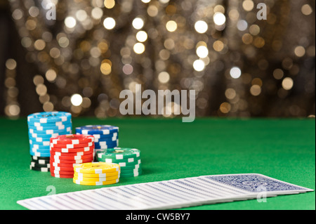 Colorato poker chips e carte di fronte a un gold glitter sfondo Foto Stock