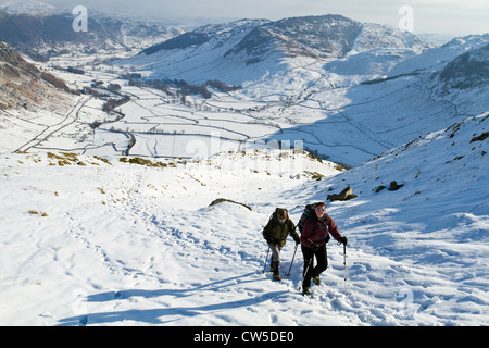 Un'immagine di due escursionisti sulla banda guardando giù al grande Langdale in condizioni invernali. Foto Stock