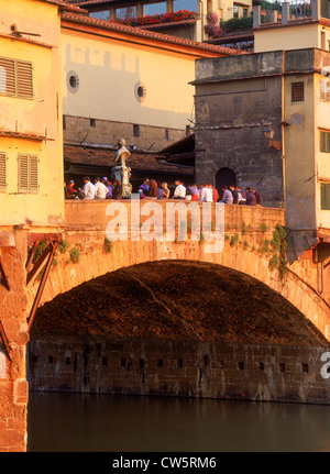 Persone relax su Ponte Vecchio oltre il fiume Arno a Firenze nella luce del tramonto Foto Stock